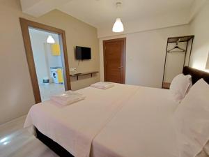 a bedroom with a large white bed and a television at Moda Hotel in Kırklareli