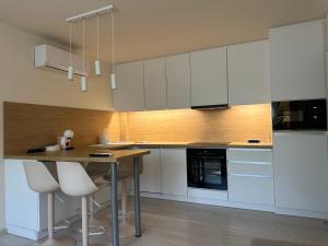 a kitchen with white cabinets and a table with stools at MiLu Apartman in Győr