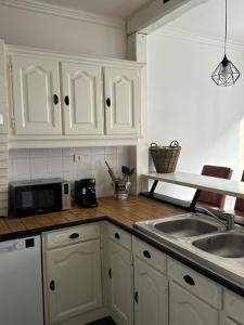 a kitchen with white cabinets and a sink and a microwave at Floc & Sens in Chalons en Champagne