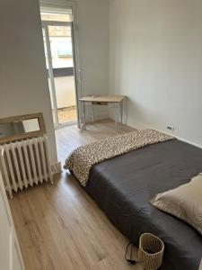 a bedroom with a bed and a table and a window at Floc & Sens in Chalons en Champagne
