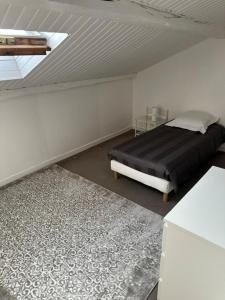 a bedroom with a bed with a black blanket and a rug at Floc & Sens in Chalons en Champagne +3 photos