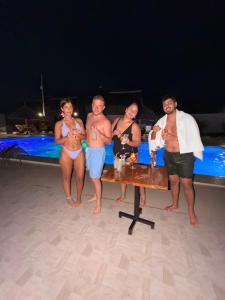 a group of people standing around a table on the beach at Wayma Paradise Resort in Jambiani