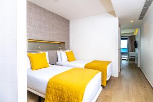 two beds in a hotel room with yellow pillows at Don Cesar Boutique Apartments in Benidorm