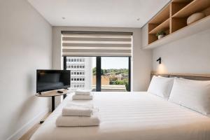 a bedroom with a white bed and a television at Argyl - The Apiary, Ealing in Ealing