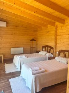 two beds in a room with wooden walls at La Hospedería Del Silencio in Robledillo de la Vera