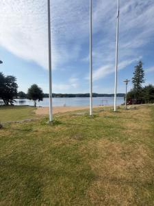 a park with poles in the grass next to a beach at Hindås Lakeside Cabin 4 in Hindås