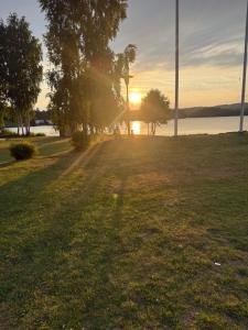 a sunset in a park with the sun setting over the water at Hindås Lakeside Cabin 4 in Hindås