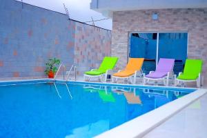 a group of colorful chairs next to a swimming pool at Studio américain Confort avec piscine in Abidjan