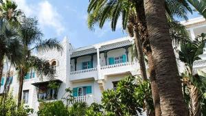 a white building with blue windows and palm trees at Chaine ELDJAZAIR by HTT in Alger