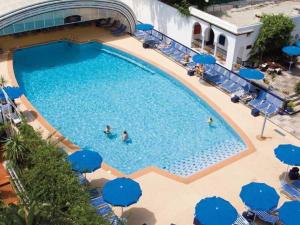 an overhead view of a swimming pool with blue umbrellas at Chaine ELDJAZAIR by HTT in Alger +3 photos