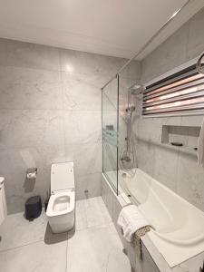 a bathroom with a tub and a toilet and a sink at Sonia Hotel in Accra