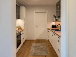 a kitchen with white cabinets and a sink at Ferienwohnung Seeperle am Dümmer See in Lembruch +30 photos