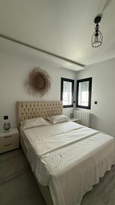 a white bedroom with a large bed with white sheets at عين زغوان in La Marsa