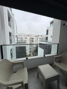 a balcony with two chairs and a large window at عين زغوان in La Marsa