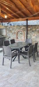 a picnic table with four chairs and a stone wall at PetroLithos Traditional Suites in Agros