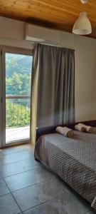 a bedroom with a bed and a large window at PetroLithos Traditional Suites in Agros