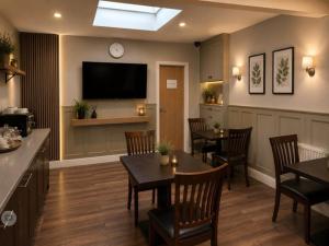 a restaurant with tables and chairs and a flat screen tv at Twickenham Guest House in Twickenham