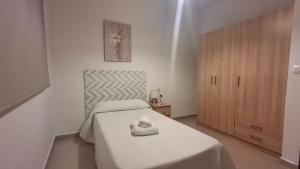 a white bedroom with a bed and a wooden cabinet at Casa Yerbabuena in La Puebla de Cazalla +15 photos