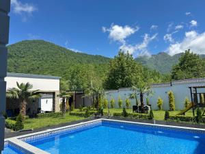 a swimming pool in a yard with mountains in the background at Palmen Villa Gabala in Gabala
