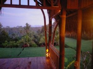 a porch of a house with a grass roof at Aska Bamboo House in Tampaksiring