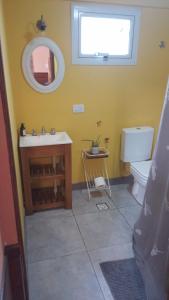 a bathroom with a sink and a toilet and a mirror at Amapolas monoambiente in El Bolsón +34 photos