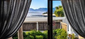 a view from a window with curtains at Peacock Cove Self Catering Studio in Gordonʼs Bay
