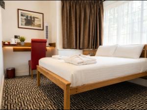 a bedroom with a bed with white sheets and a window at Twickenham Guest House in Twickenham