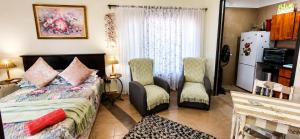 a bedroom with a bed and two chairs at Peacock Cove Self Catering Studio in Gordonʼs Bay