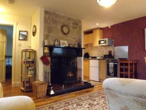 a living room with a fireplace and a kitchen at Small cosy bothy in Dingwall
