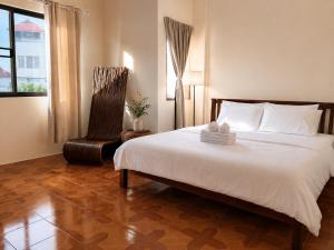 a bedroom with a large white bed and a chair at inghome & guesthouse in Chiang Mai