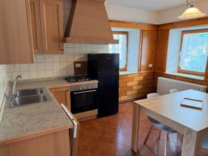 a kitchen with a black refrigerator and a table at Appartamento Girasole - Cadore Apartments in Candide +12 photos