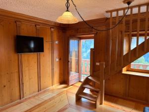 a living room with a staircase and a tv in a house at Appartamento Girasole - Cadore Apartments in Candide