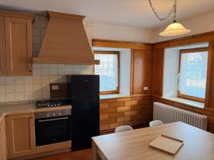 a kitchen with a black refrigerator and a table at Appartamento Girasole - Cadore Apartments in Candide