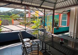 a glass table and chairs in a room with a window at Thilo Guest House Auroville in Auroville