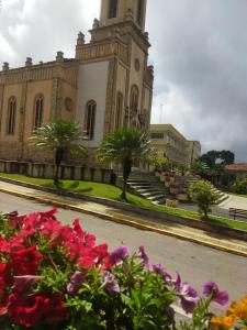 a church with a clock tower with flowers in the foreground at Casa das Petúnias in Ubajara