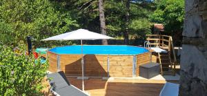 ein Pool mit Sonnenschirm neben einer Holzterrasse in der Unterkunft Authentique-CAVE Les Assions in Les Assions