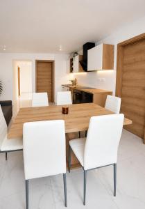 a dining room with a wooden table and white chairs at Apartma 47 in Kobarid +14 photos