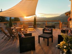 a deck with chairs and a table and a sunset at Les Garianes in Saint-Léger-les-Mélèzes