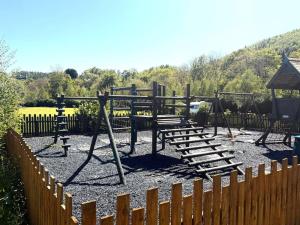 a park with a playground with a wooden fence at Glamping Hut - Sleeps 2 hot tub & parking in Garthbeibio