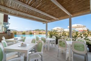 a patio with tables and chairs and a pool at Residence Le Fontane in Villasimius