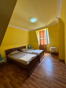a bedroom with a bed with yellow walls and wooden floors at Beka's GuestHouse in Gonio