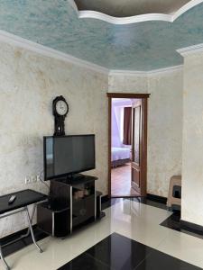 a living room with a tv and a clock on the wall at Beka's GuestHouse in Gonio