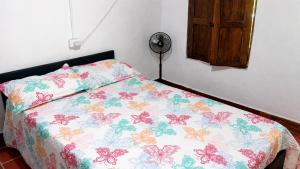 a bedroom with a bed with a floral comforter at Finca de las banderas in Jardin