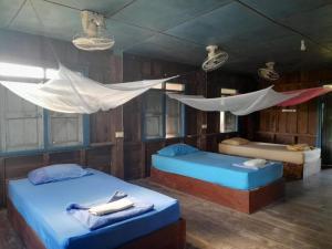 a room with two beds and a hammock in it at Nature Dormitory in Ban Donsôm Tai
