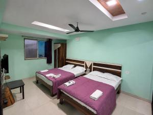 a bedroom with two beds and a ceiling fan at Sunset View in Mahabaleshwar
