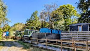 a row of tiny homes in a fence at Glamping Hut - Sleeps 2 hot tub & parking in Garthbeibio