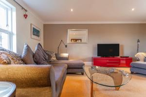 a living room with a couch and a tv at Links Lodge - Blacklaws Steading in Anstruther
