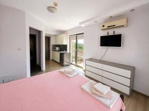 a bedroom with a large pink bed and a kitchen at Хотел Дани in Sandanski