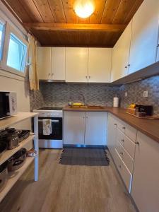a kitchen with white cabinets and a wooden ceiling at Elia House in Skopelos Town