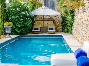 a swimming pool with an umbrella and some chairs and an umbrella at Villa Sunset in Gordes in Gordes